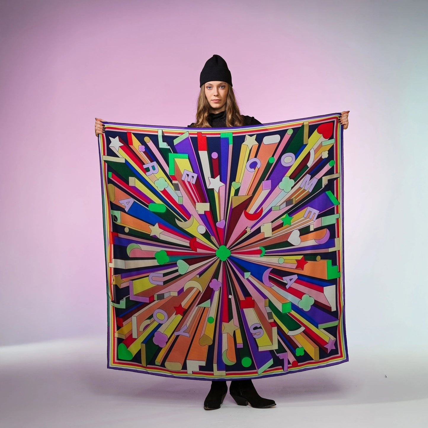 Frau mit schwarzer Mütze hält buntes Seidentuch Grand Foulard mit grafischem Muster und Schriftzug von Foulala Luzern