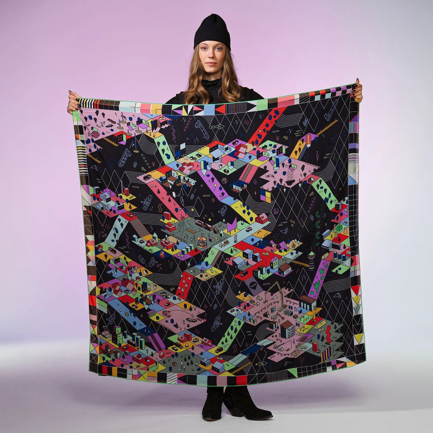 Frau mit schwarzer Mütze hält quadratisches, bunt gemustertes Seidentuch vor lila Hintergrund.