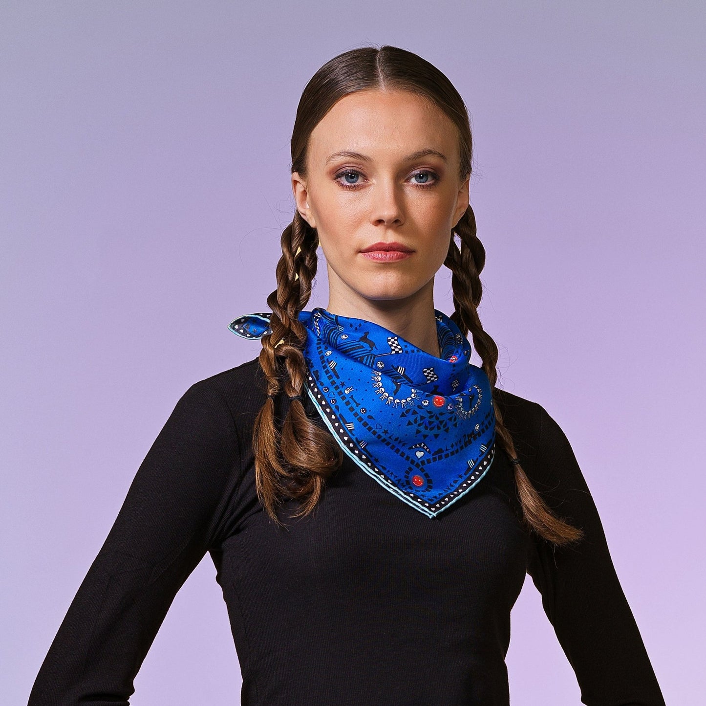 Frau mit schwarzem Shirt trägt blaues Woll-Bandana mit schwarz-weissem Muster, groten Akzenten und illustrierten Details