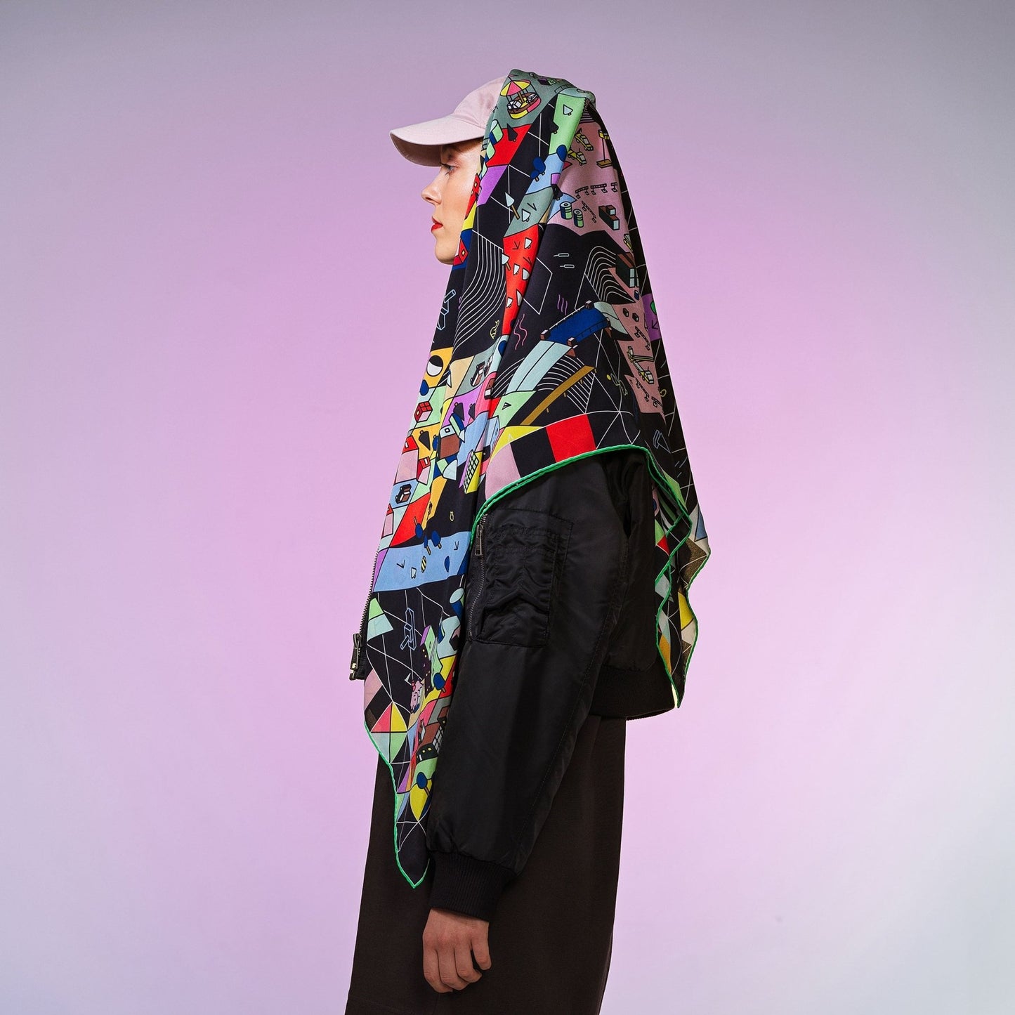 Frau mit rosa Mütze trägt quadratisches, bunt gemustertes Seidentuch auf dem Kopf vor pastellig, lila Hintergrund.