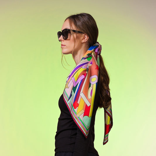 Frau mit bunter Seiden-Carré, geometrisches Muster, pastellfarbenem Studiohintergrund, Modeaccessoire