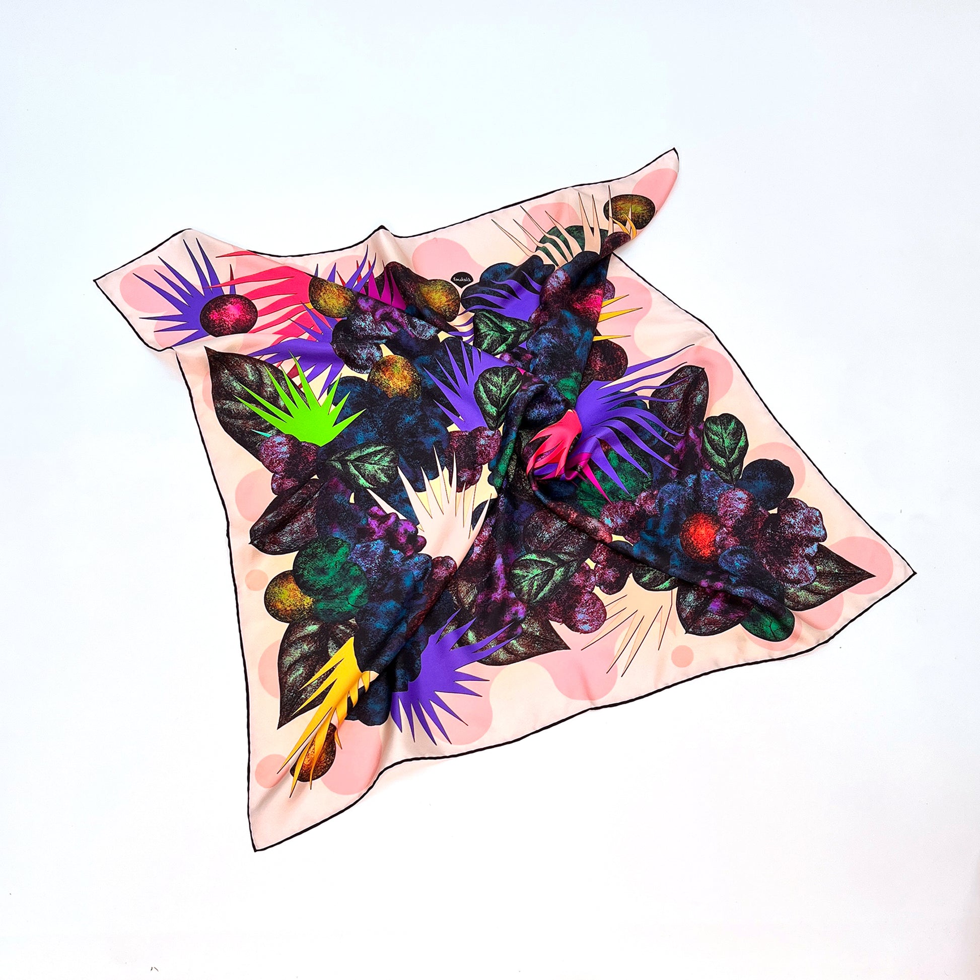 Buntes Tuch mit wildem Blumenmuster mit Blättern ausgebreitet auf hellem Hintergrund